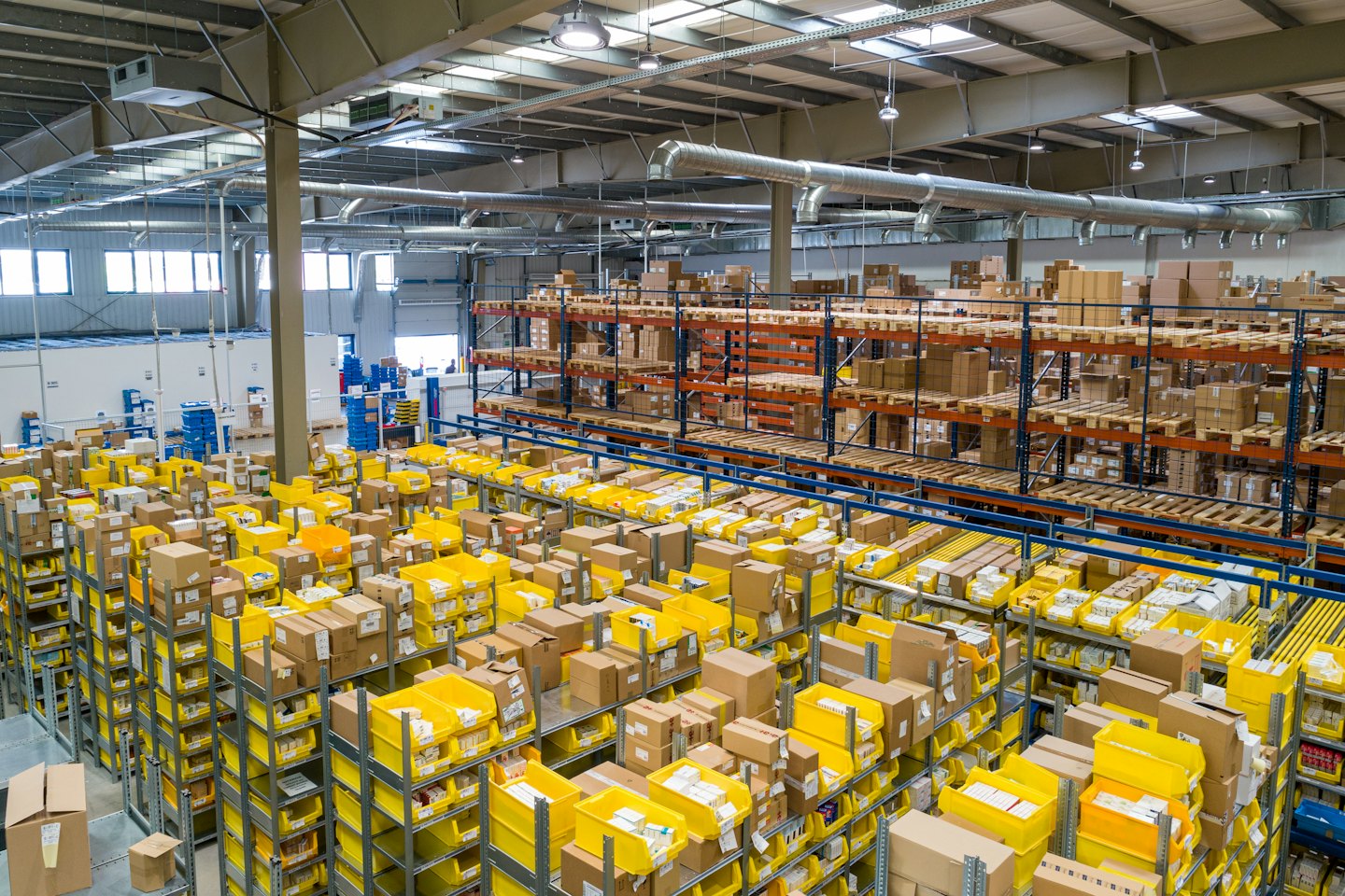Rows of shelves filled with cardboard boxes and yellow bins.
